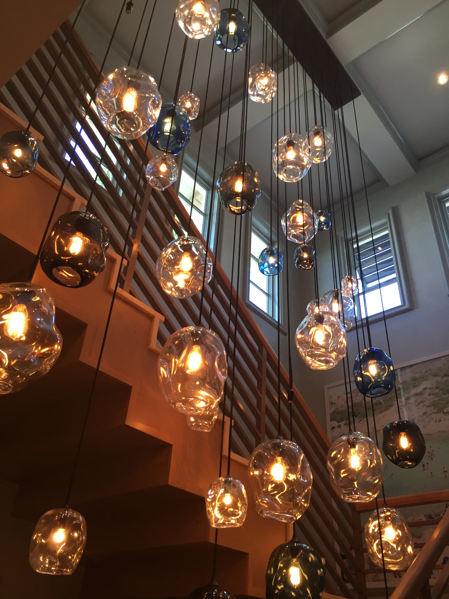 Cluster of hand-blown glass orb pendants hung at staggered heights in a stairwell