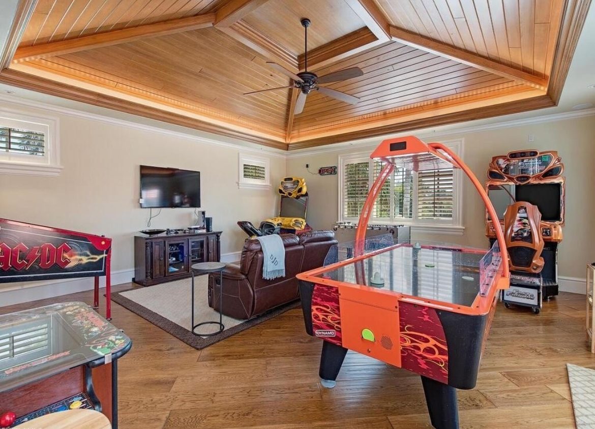 Game room with a wood tray ceiling lit by concealed cove lighting