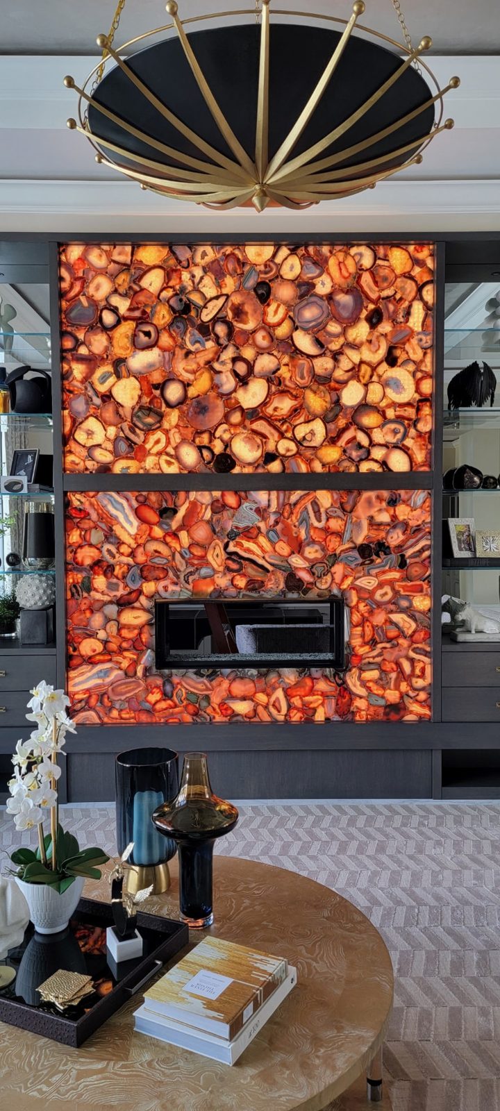 Backlit agate stone feature wall with a linear fireplace and a gold starburst ceiling fixture