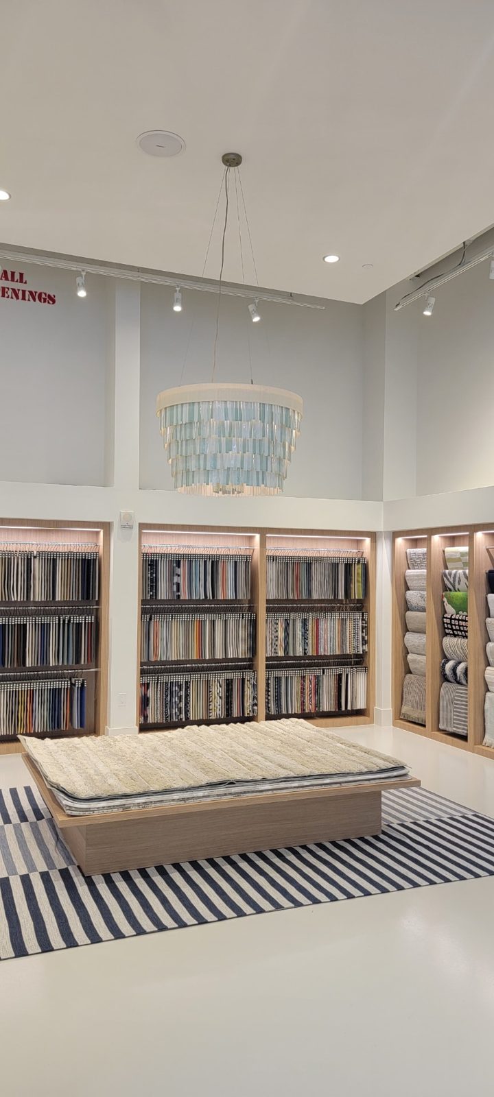 Retail showroom with a tiered pendant fixture, track lighting and lit display shelving