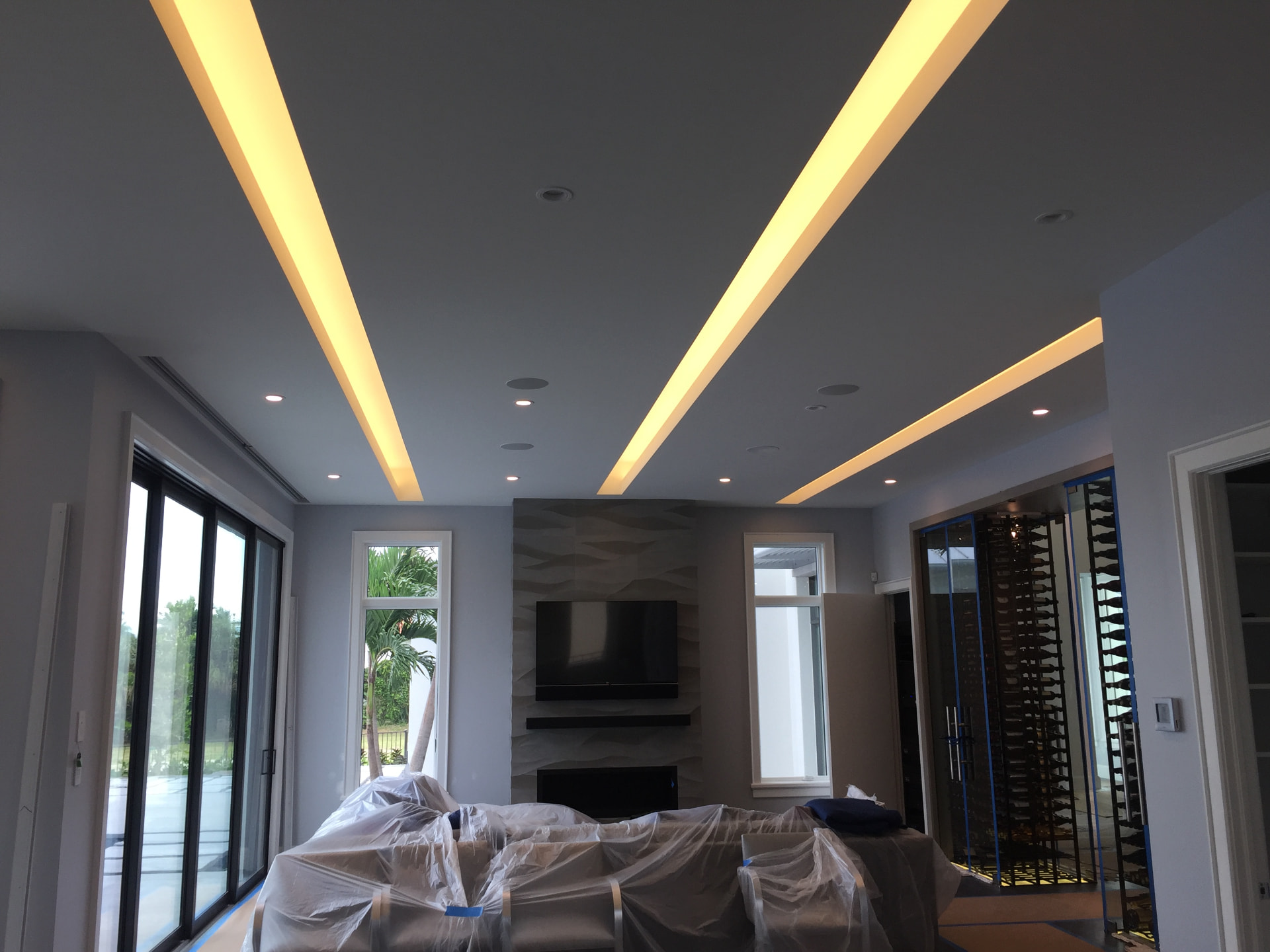 Living room ceiling with recessed linear cove lighting channels and recessed cans